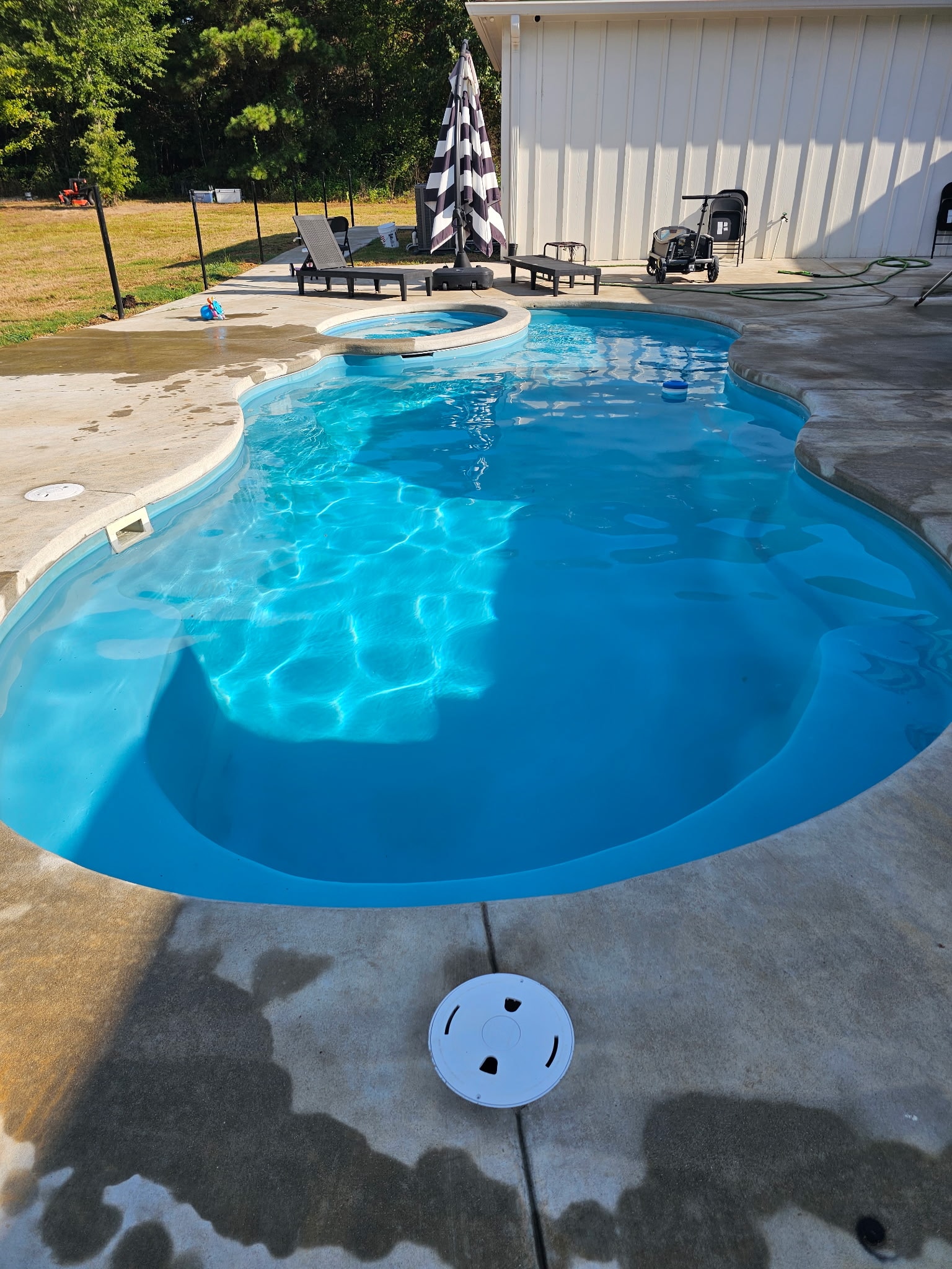 Freeform pool with attached spa and concrete deck
