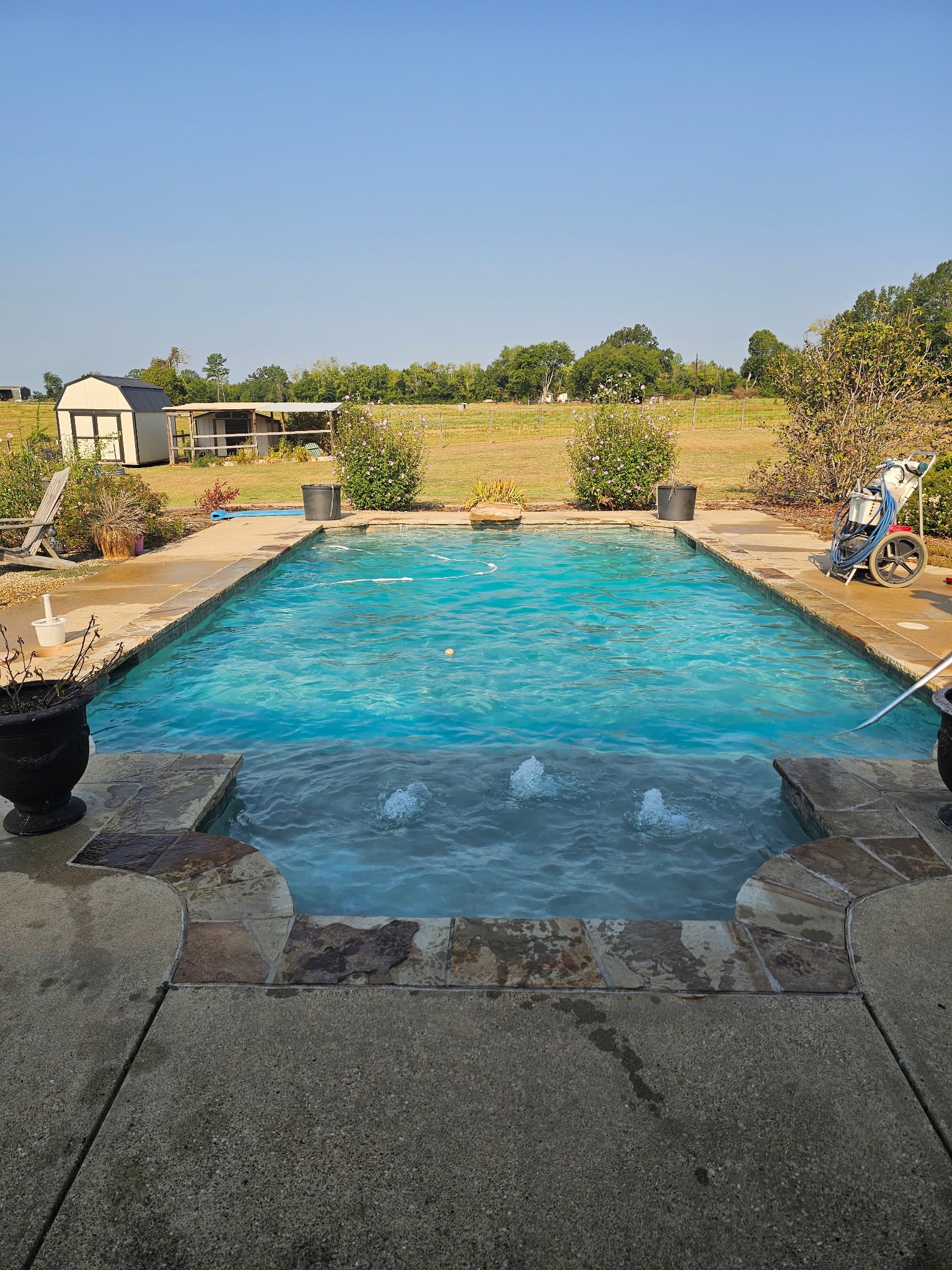 Rectangular pool being serviced in rural East Texas setting