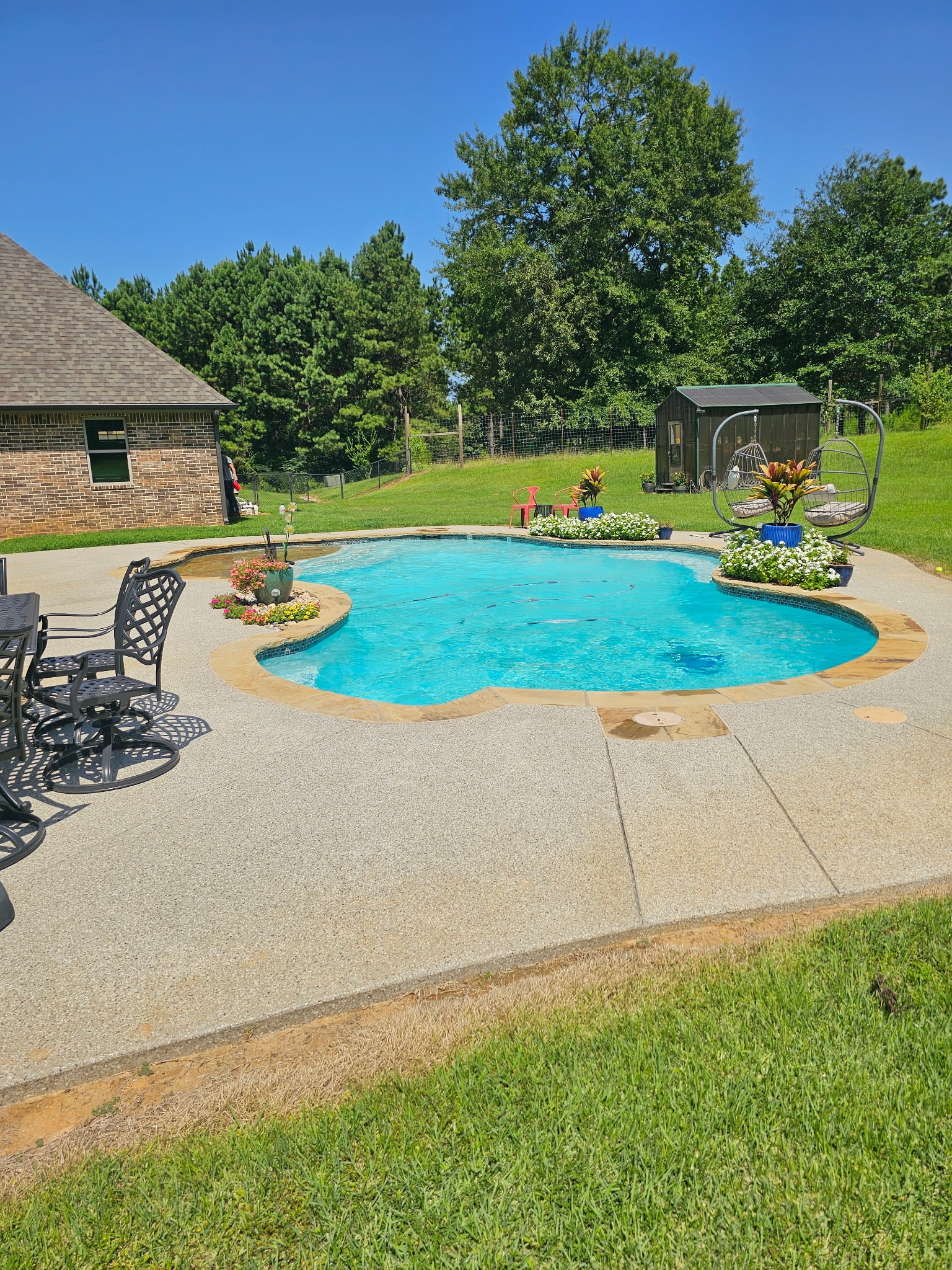 Freeform pool with flower beds and patio furniture